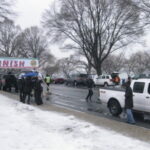Here's an alt tag for the image: Snowy race finish line with people.