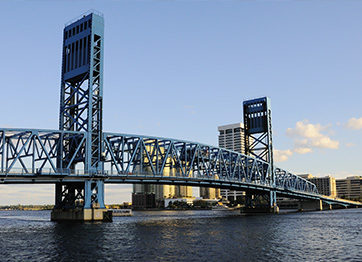 Here's an alt tag for the image: Blue drawbridge over calm water.