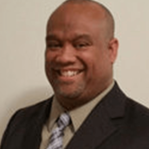 Headshot of a smiling man in a suit.