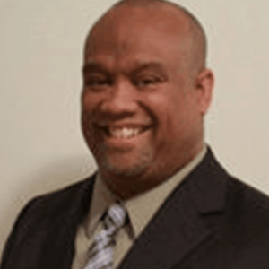 Headshot of a smiling man in a suit.